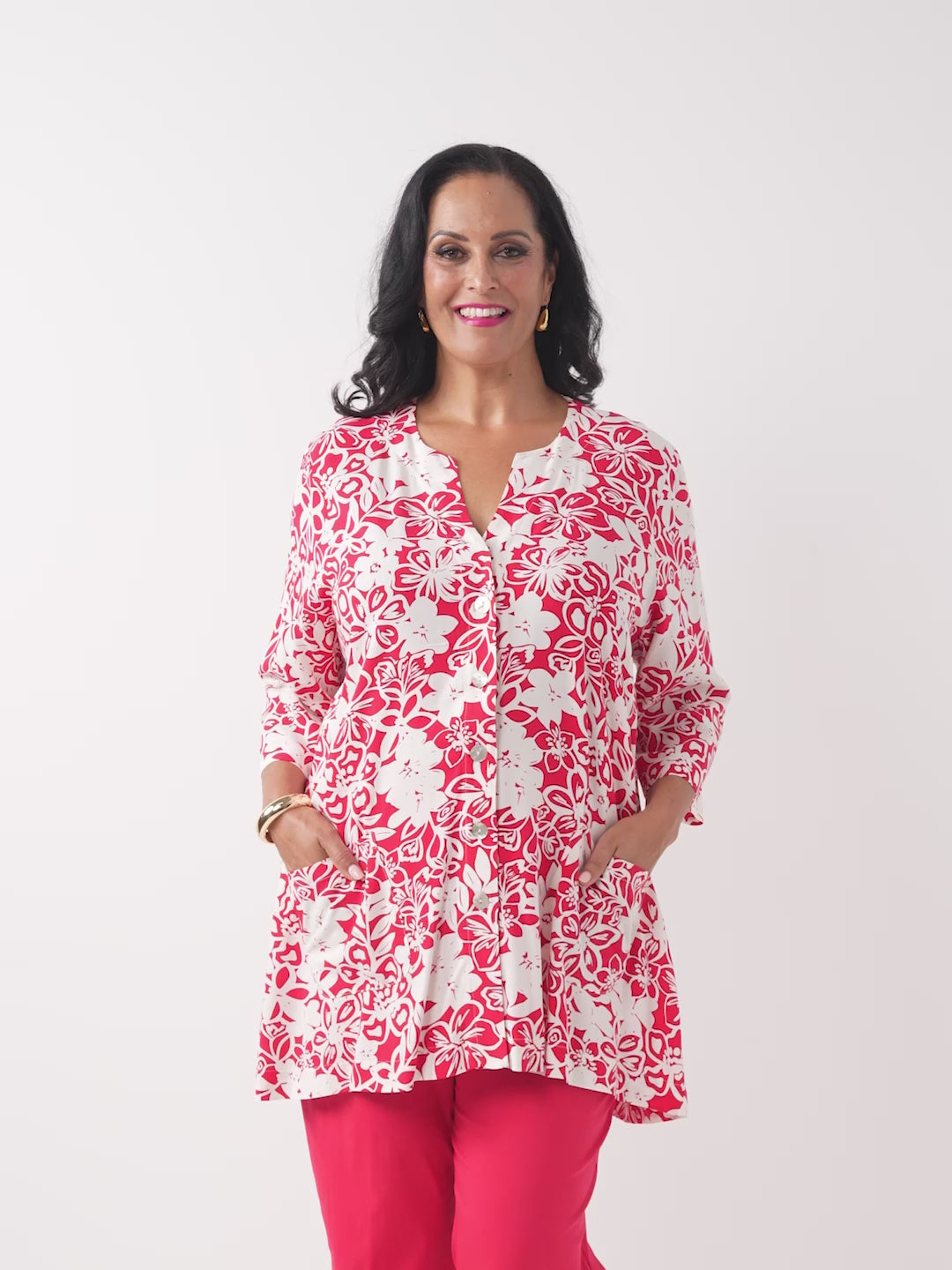 A woman wearing a red and white floral print tunic top with three-quarter sleeves, paired with red pants