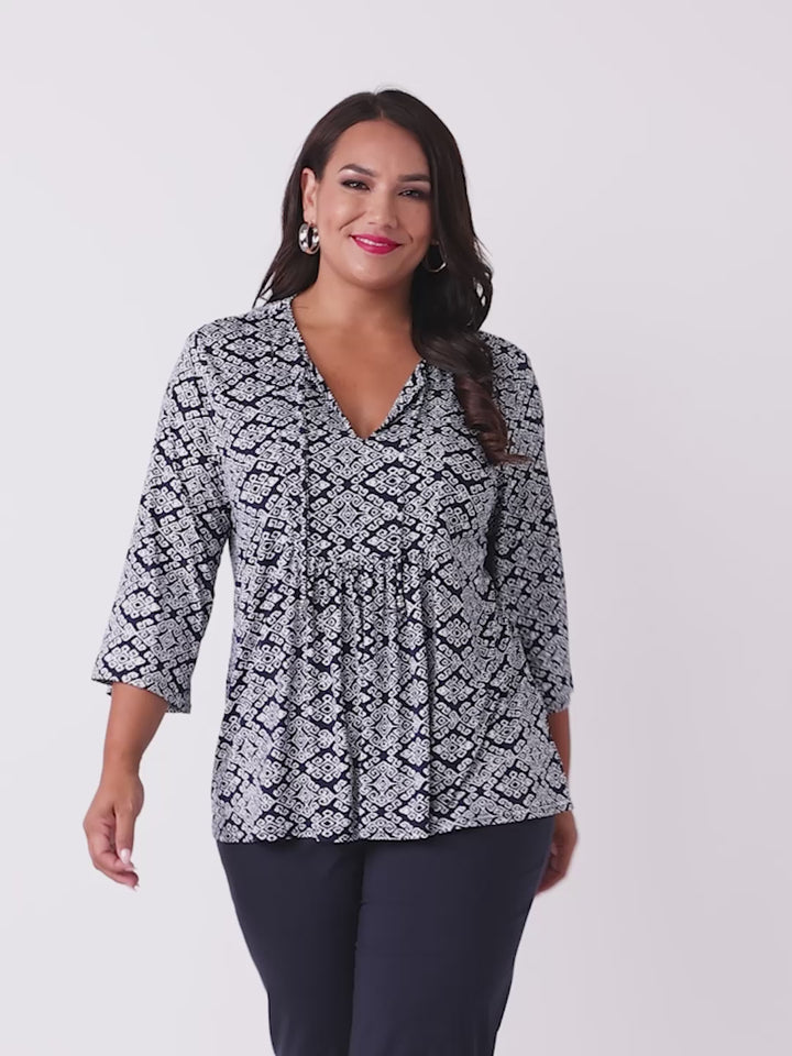 A video of a woman wearing a navy blue and white printed top with three-quarter sleeves and front tie